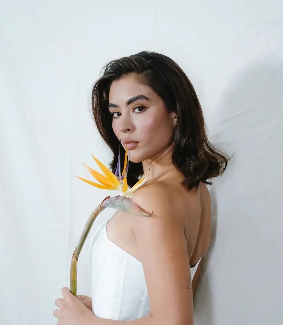 Bride in a strapless gown holding a bird of paradise