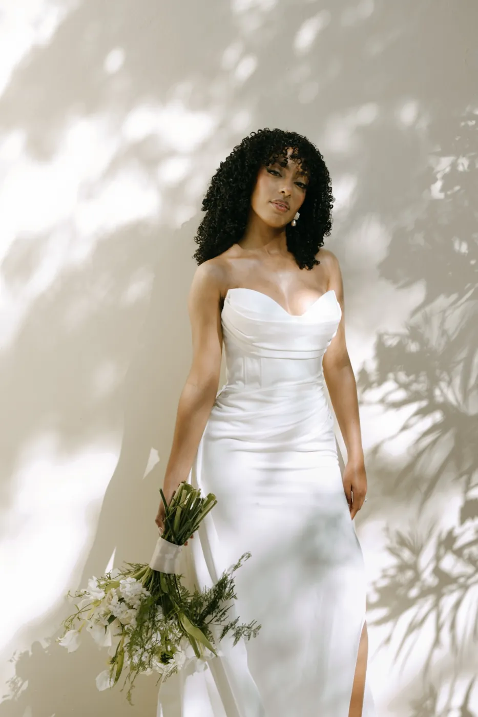 Bride holding a loose bouquet in dappled light