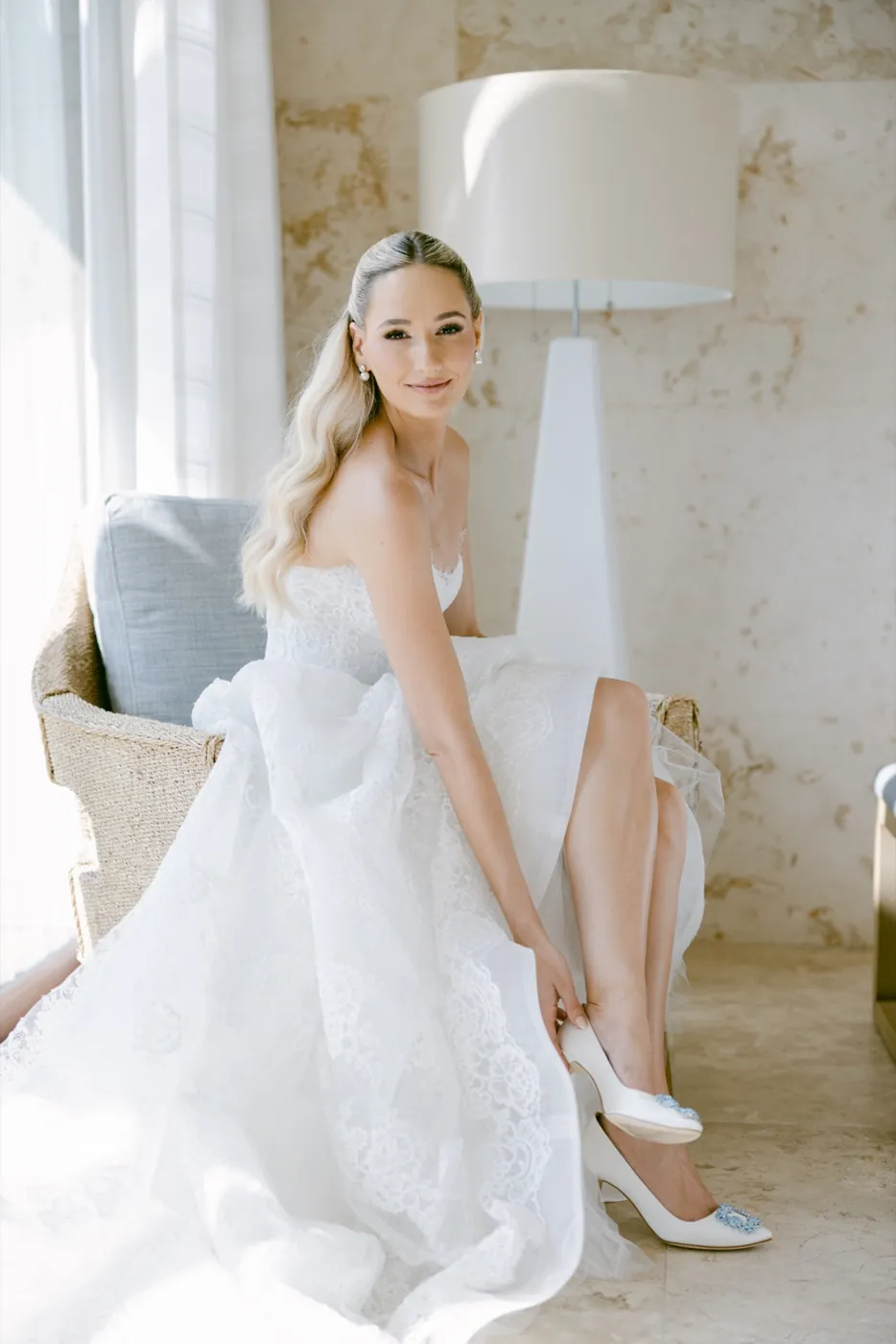 Celine putting on her shoe in a sunlit room, relaxed in her gown