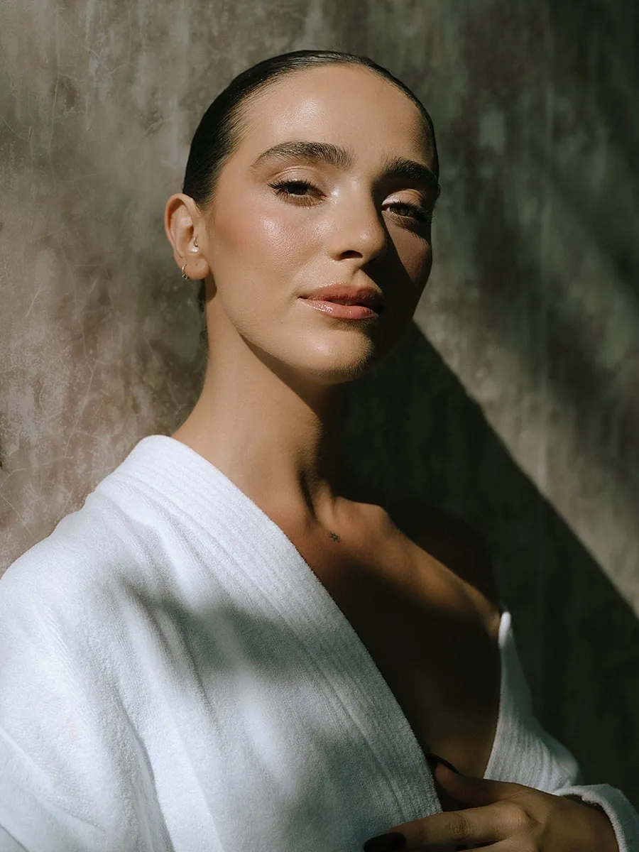 Bride in a white robe with sculpted, glowing skin and a soft nude lip