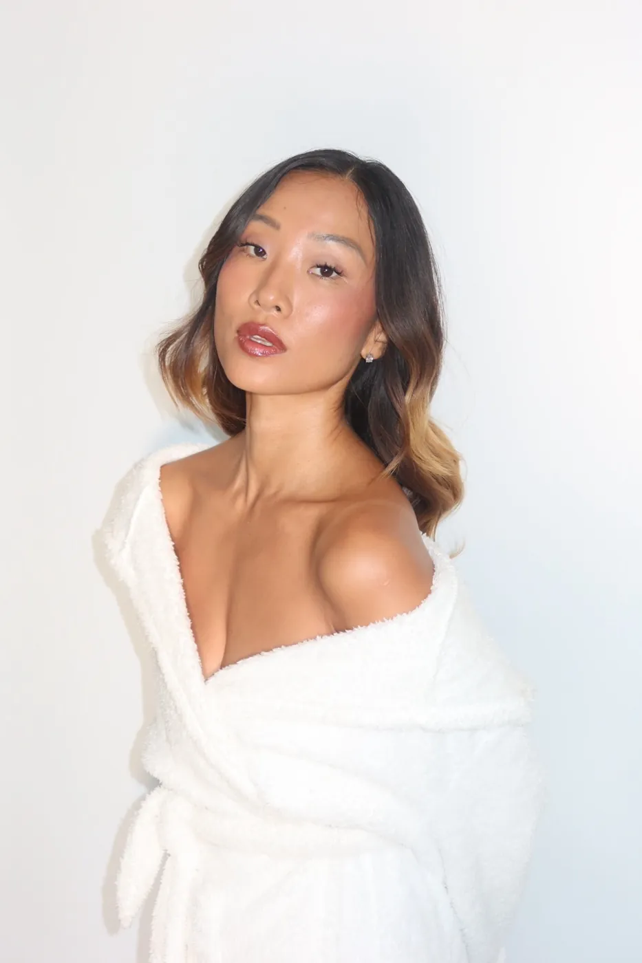 Model in a white robe with warm, glowing skin